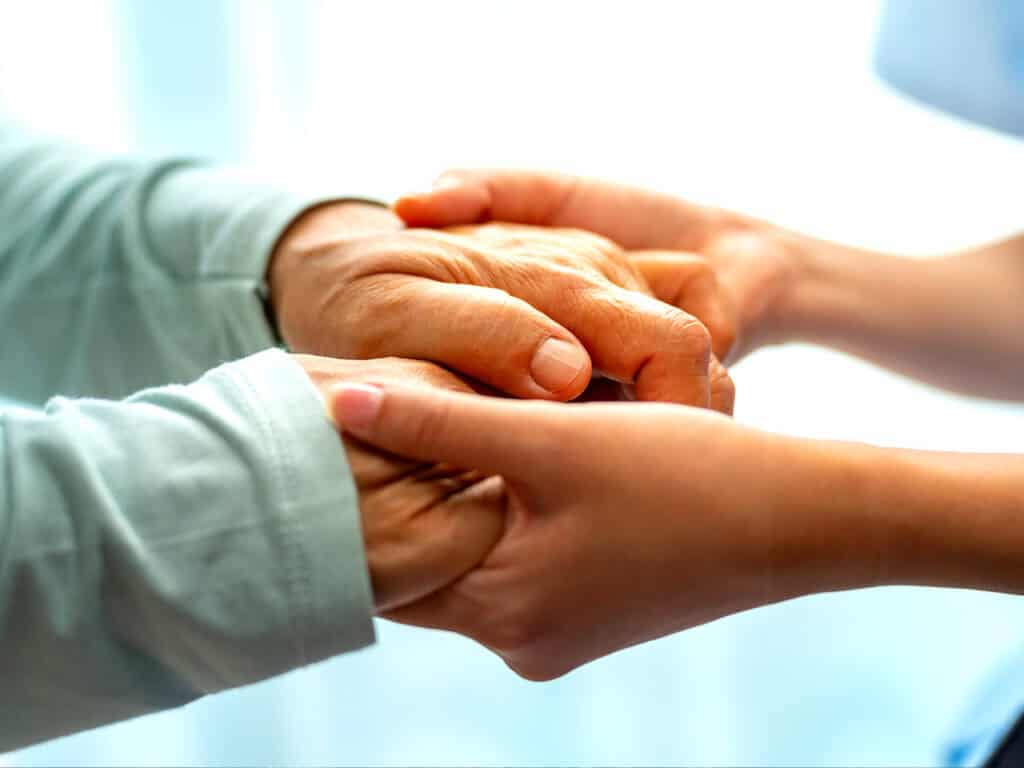 Elderly woman holding hands with young female