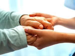 Elderly woman holding hands with young female