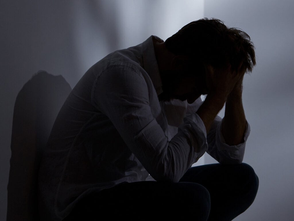 Crouching man with hands on his head