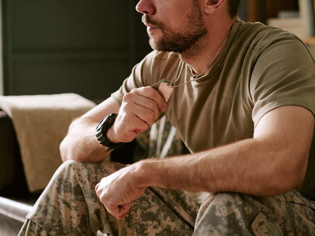 Man in fatigues holding dog tags
