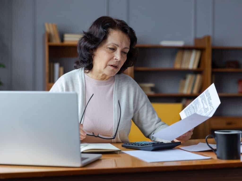 Middle aged woman sitting with laptop and documents